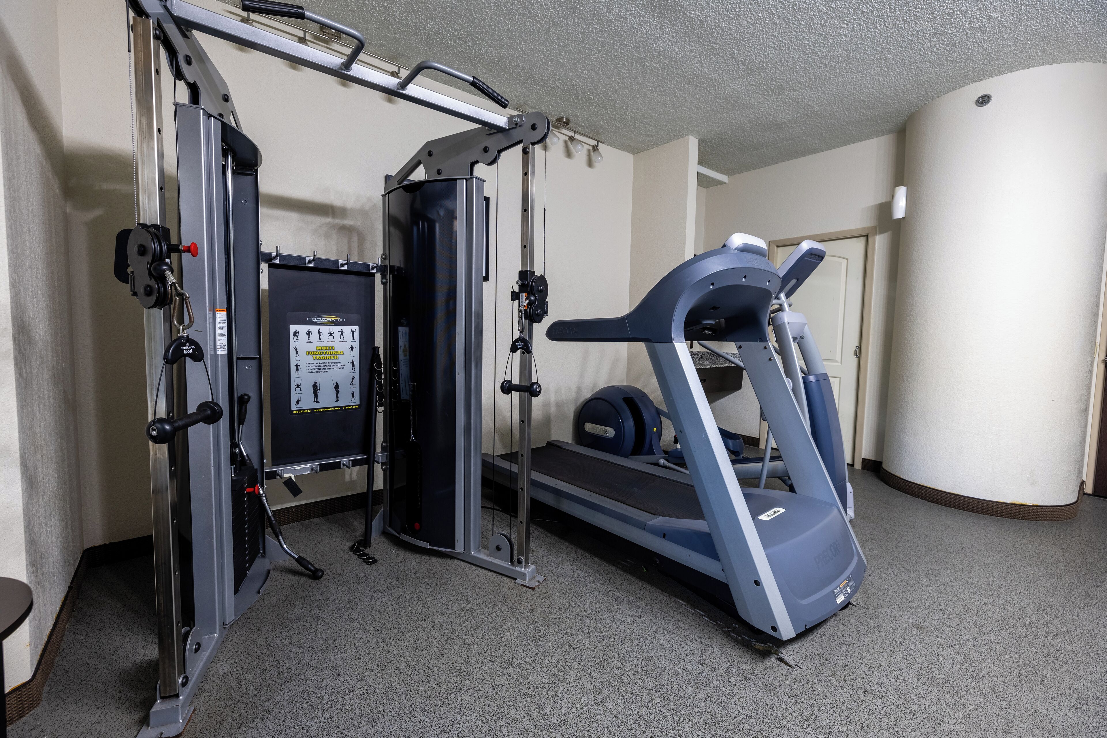 Et hjemmegym med trækstang, vægtbænk og løbebånd.