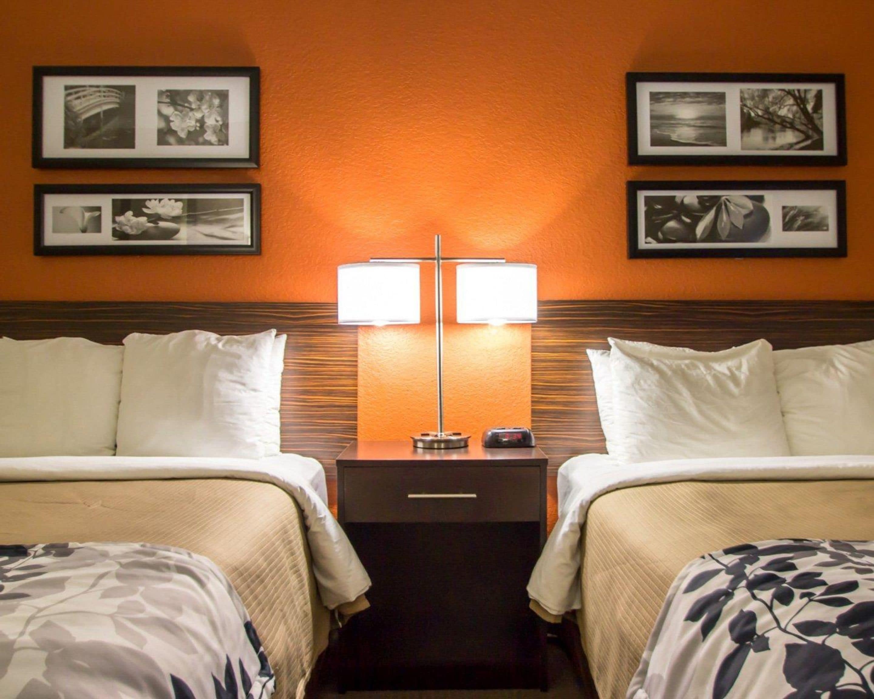 Una habitación de hotel con dos camas, una mesita de noche con lámpara y cuadros en la pared.