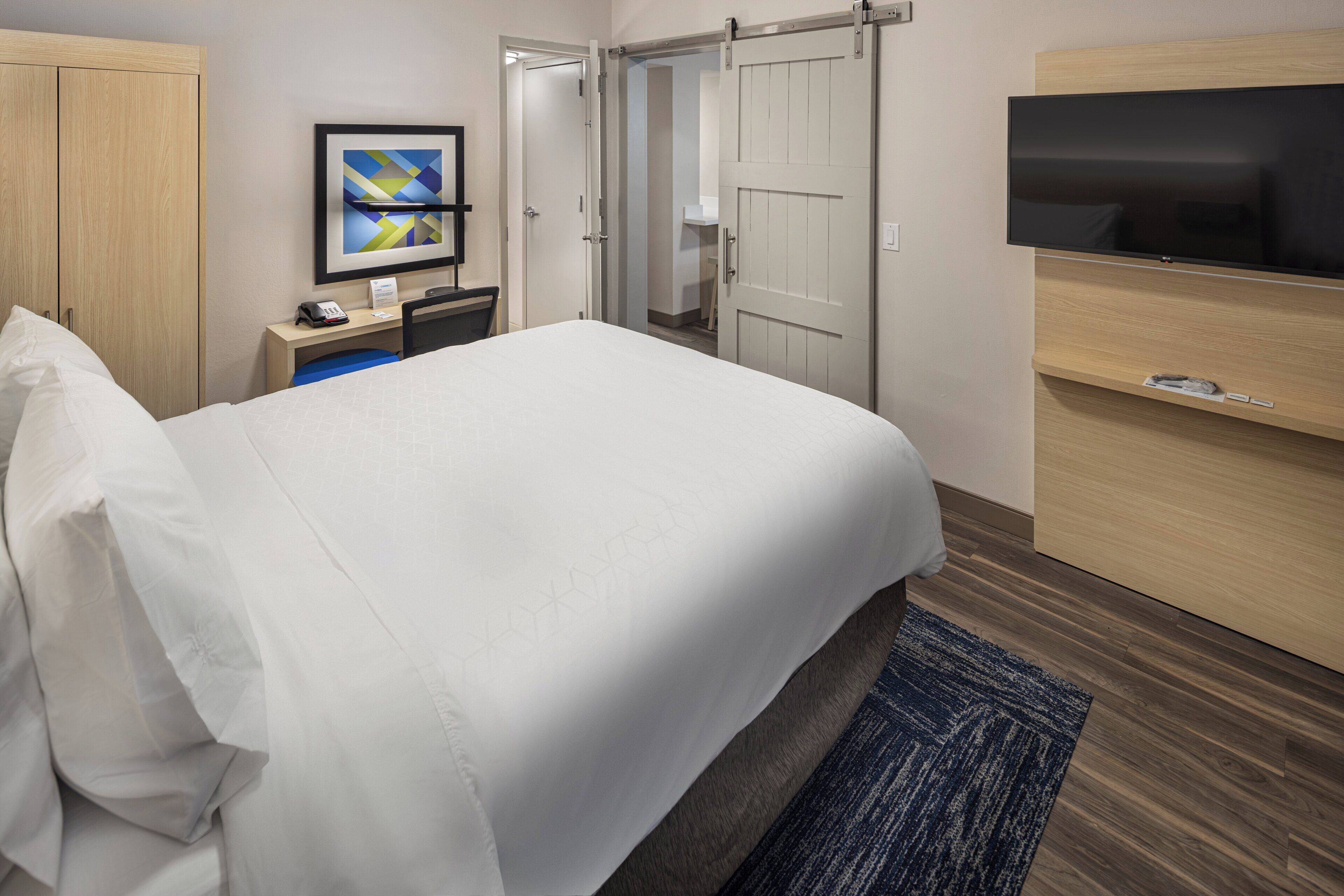 A hotel room with a bed, a desk, a TV, and a wardrobe.