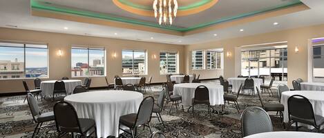 A conference room with round tables, chairs, and a chandelier.