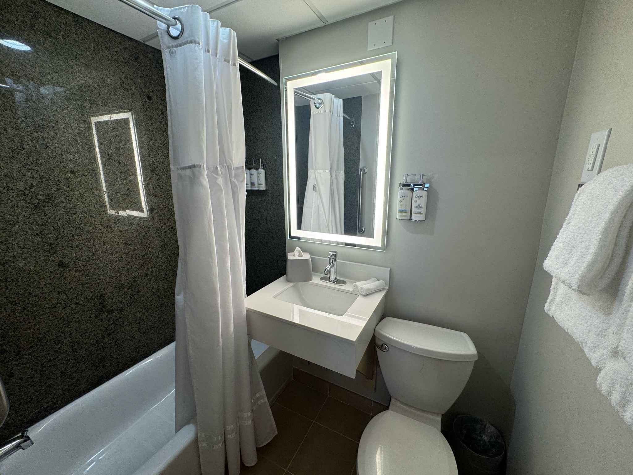 A bathroom with a bathtub, a sink, a toilet, and a mirror.