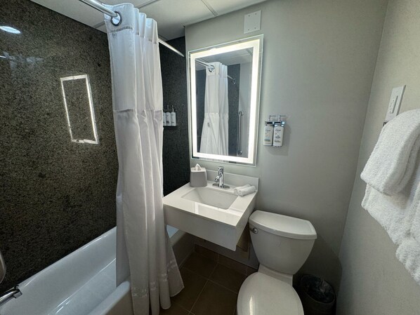 Un baño con bañera, lavamanos, inodoro y espejo.