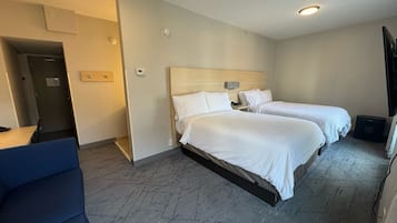 Een hotelkamer met twee bedden, een bureau en een stoel.
