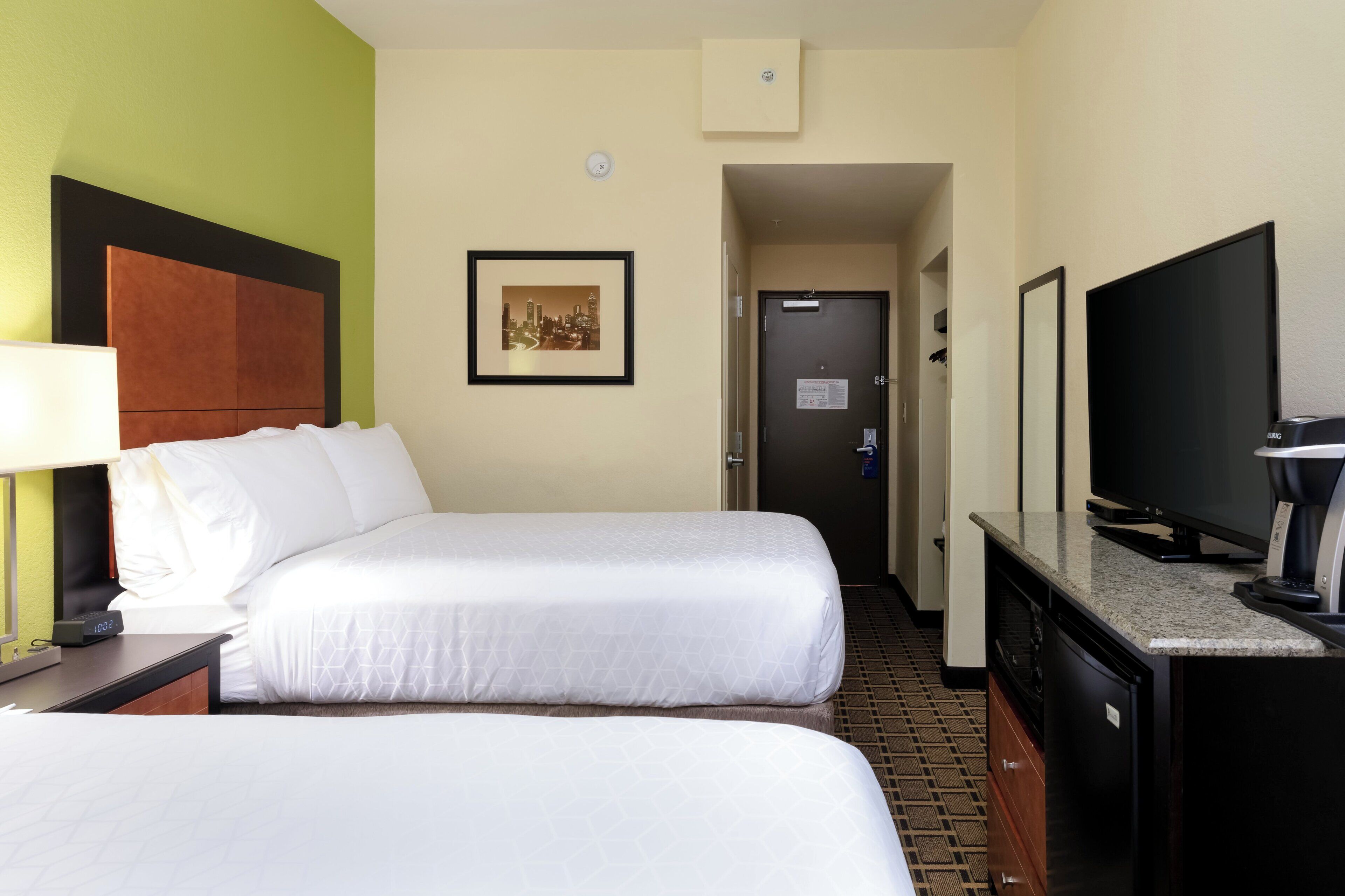 Una habitación de hotel con dos camas, televisión y cafetera.