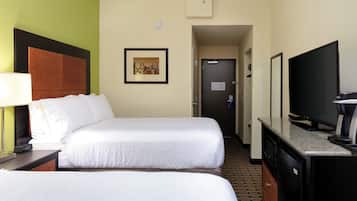 Una habitación de hotel con dos camas, televisión y cafetera.