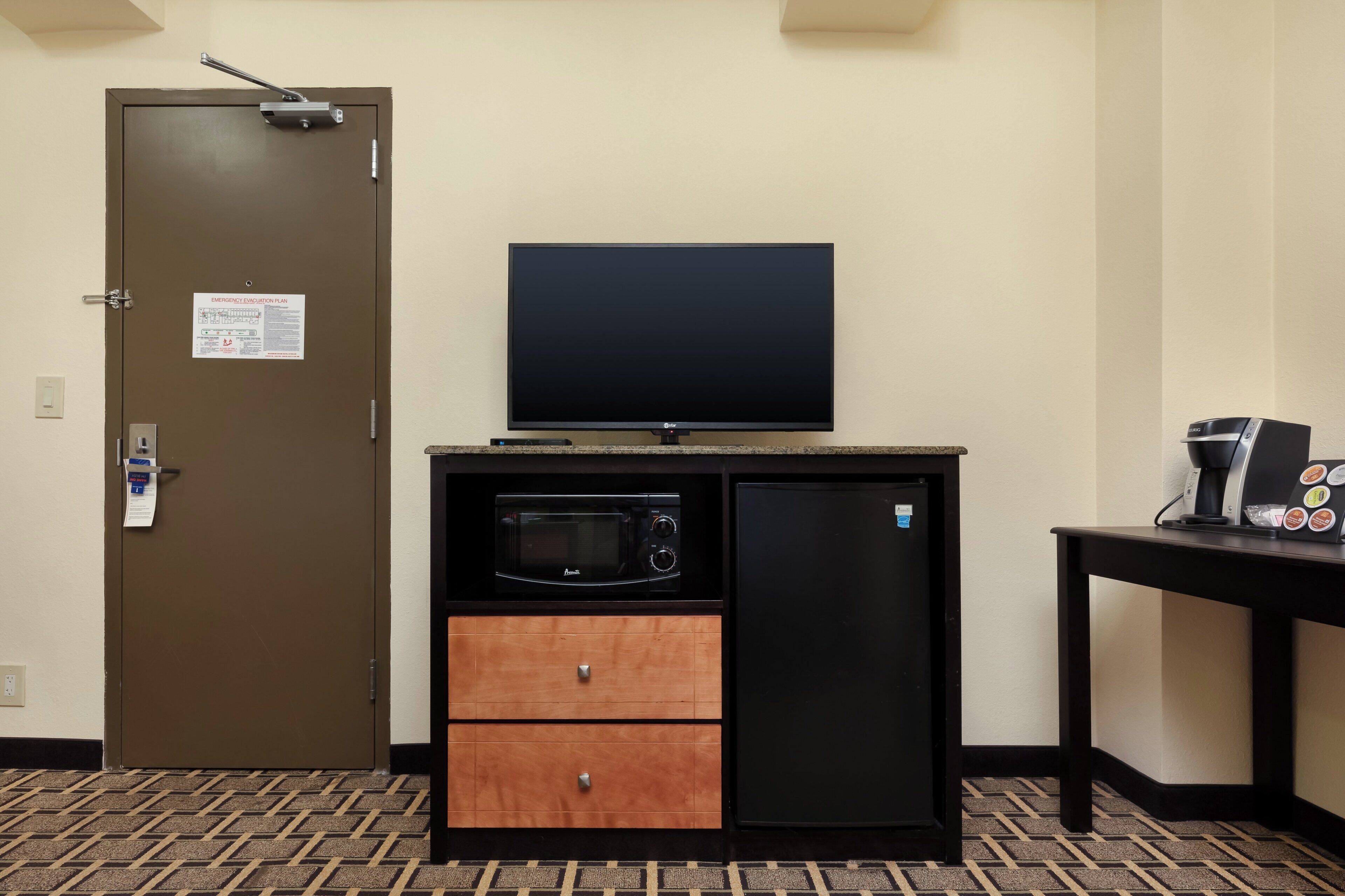 A kitchenette with a microwave, refrigerator, and a flat-screen TV.