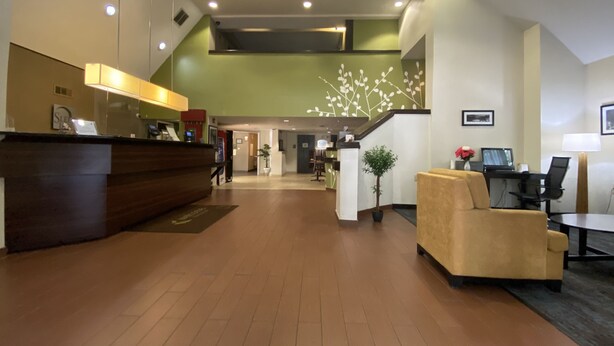 Rebedor d'hotel amb taulell de recepció, escala, zona de seients i mostrador d'informació.