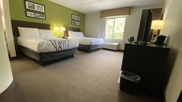 A hotel room with two beds, a desk with a mirror, and a window with curtains.