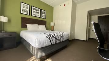 Une chambre d’hôtel avec un lit, deux tables de chevet avec des lampes, une tête de lit et des tableaux encadrés au mur.