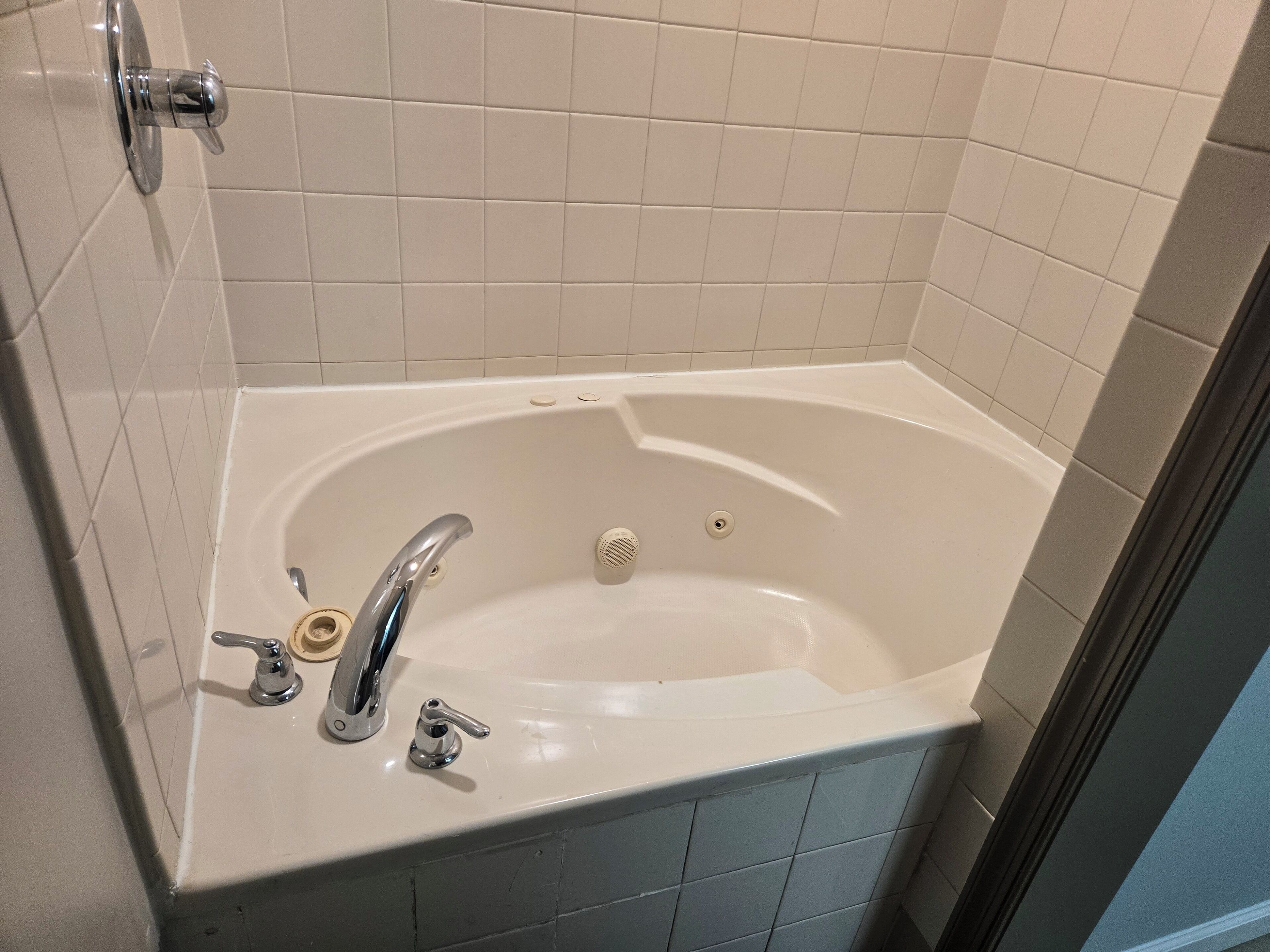 Un baño con una bañera blanca, un solo grifo y un cabezal de ducha.
