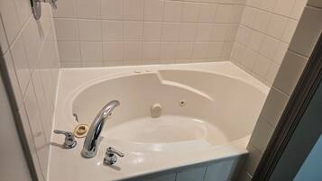 Une salle de bain avec une baignoire blanche, un seul robinet et une pomme de douche.