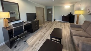 Un salon moderne comprenant un téléviseur à écran plat, un bureau avec des tiroirs, un canapé et une table basse.