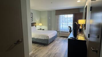 A hotel room with a bed, a desk with a television, and a wardrobe.