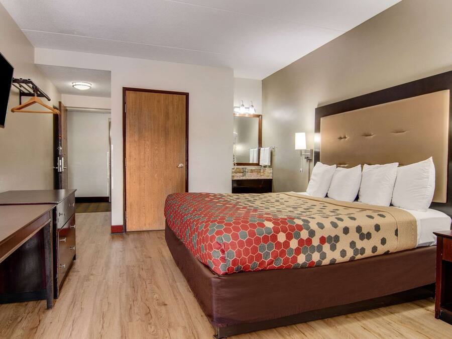 Een hotelkamer met een groot bed, een bureau, een televisie en een spiegel.