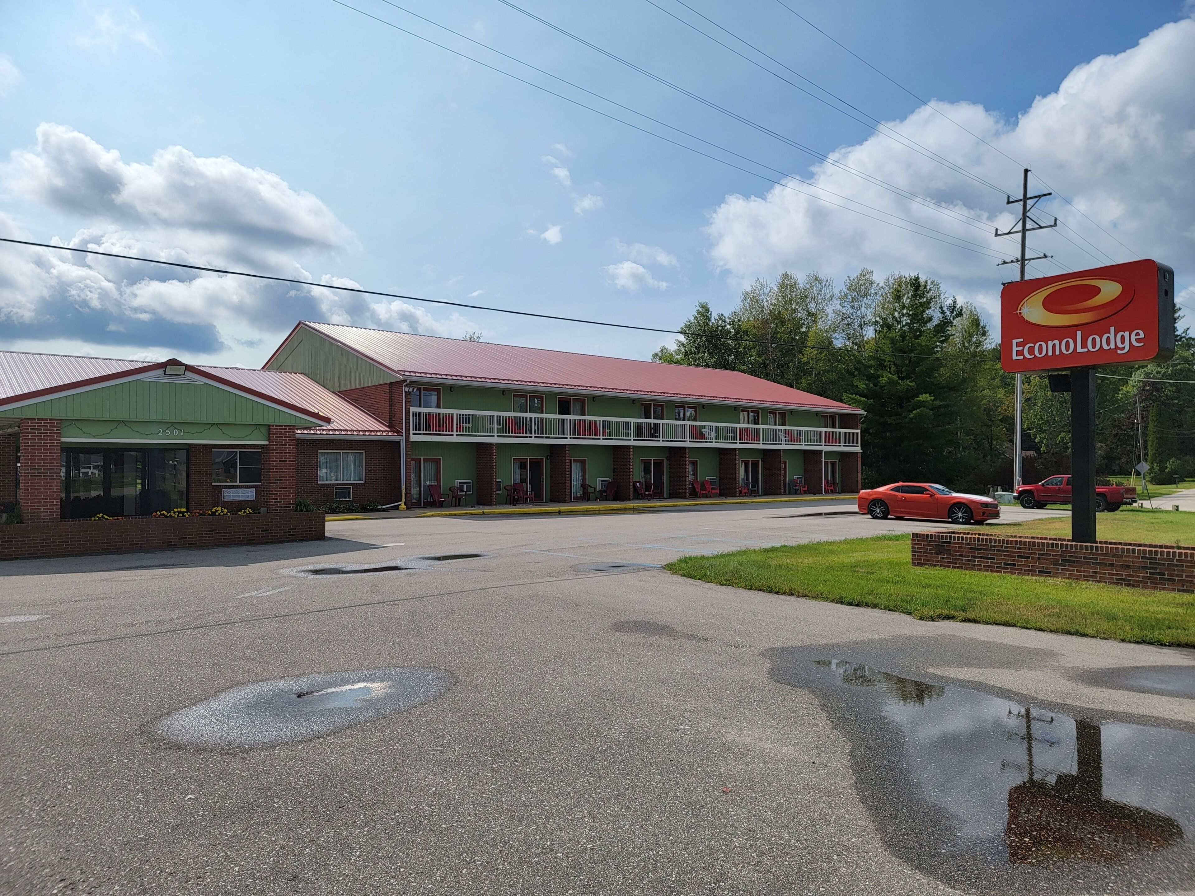 A two-story motel with a green facade and a red roof, featuring a parking lot and a sign for EconoLodge.