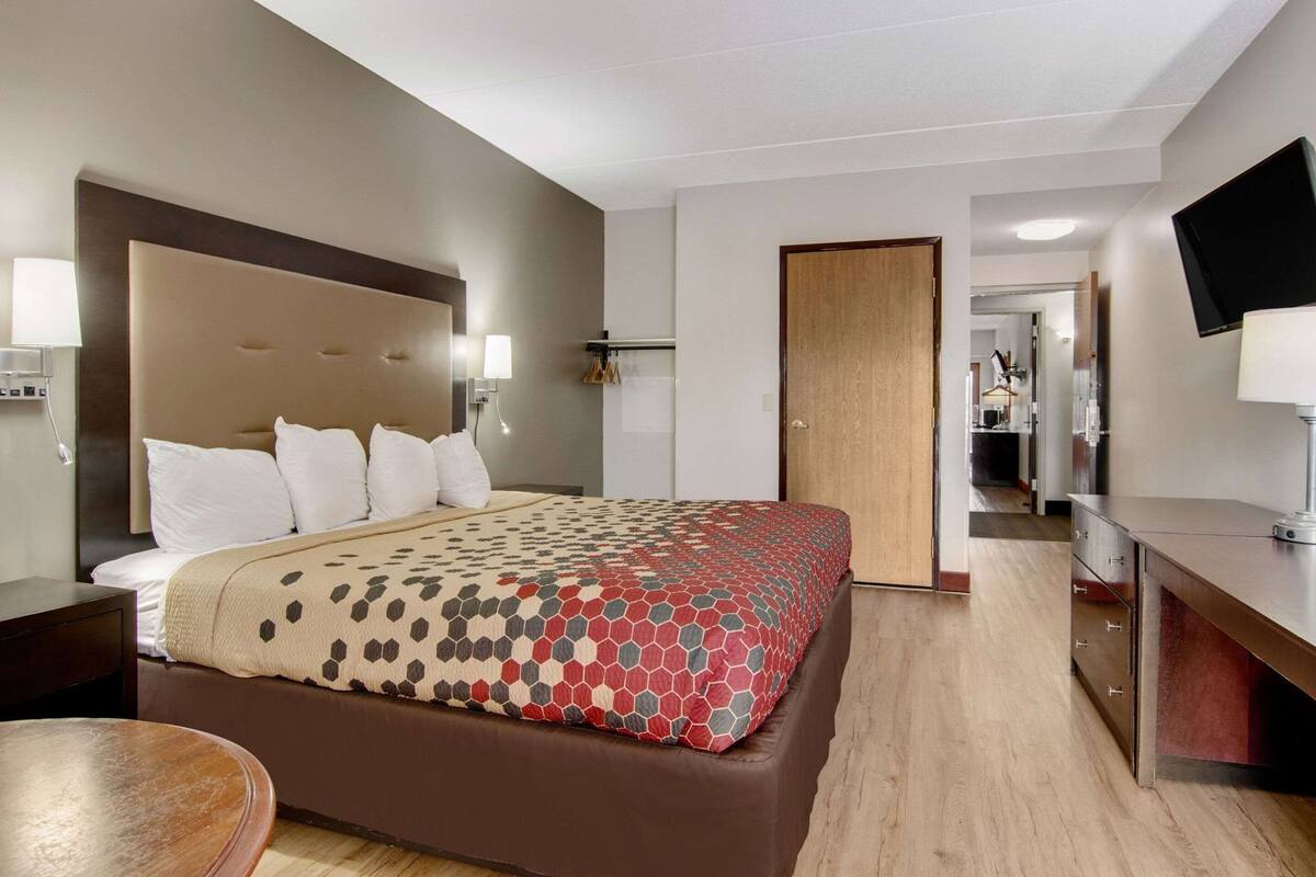 A hotel room with a bed, bedside tables, a desk, a TV, and a wardrobe.