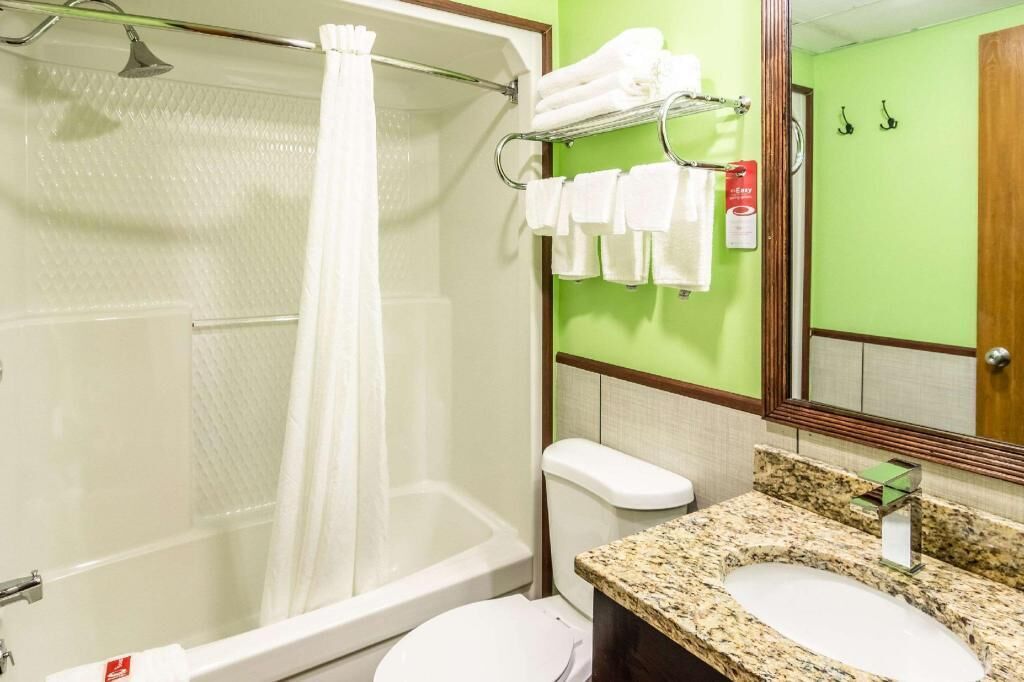 A bathroom with a shower, toilet, sink, and towel rack.