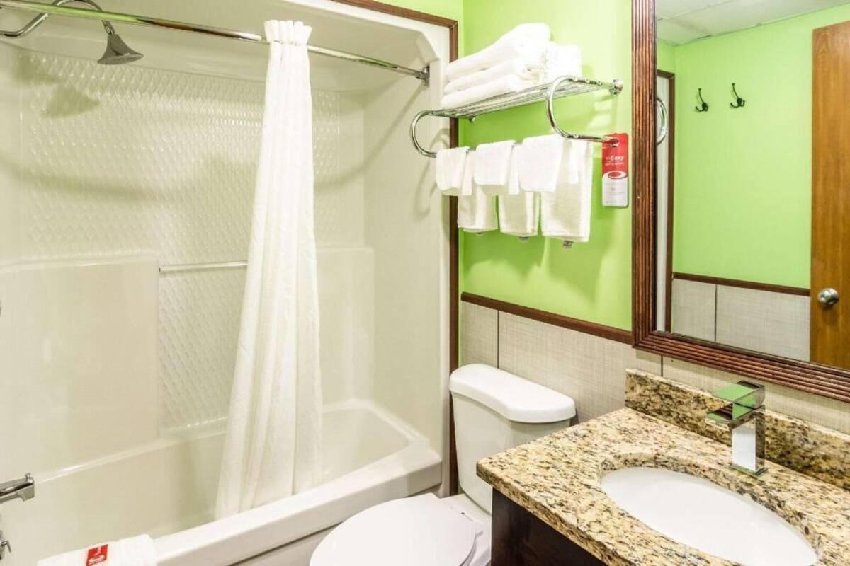 A bathroom with a shower, toilet, sink, and towel rack.