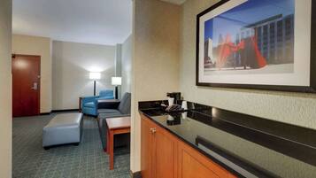 A hotel room with a sofa, a small table, a cabinet, and a framed picture on the wall.
