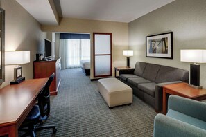 Relax in a comfortable seating area with a sofa, ottoman, and desk, perfect for unwinding.