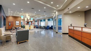 Un vestíbulo amplio con mostrador de recepción, zona de estar y una escalera que conduce a los pisos superiores.