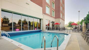 A pool area with a clear pool, a no diving sign, and outdoor seating with umbrellas.