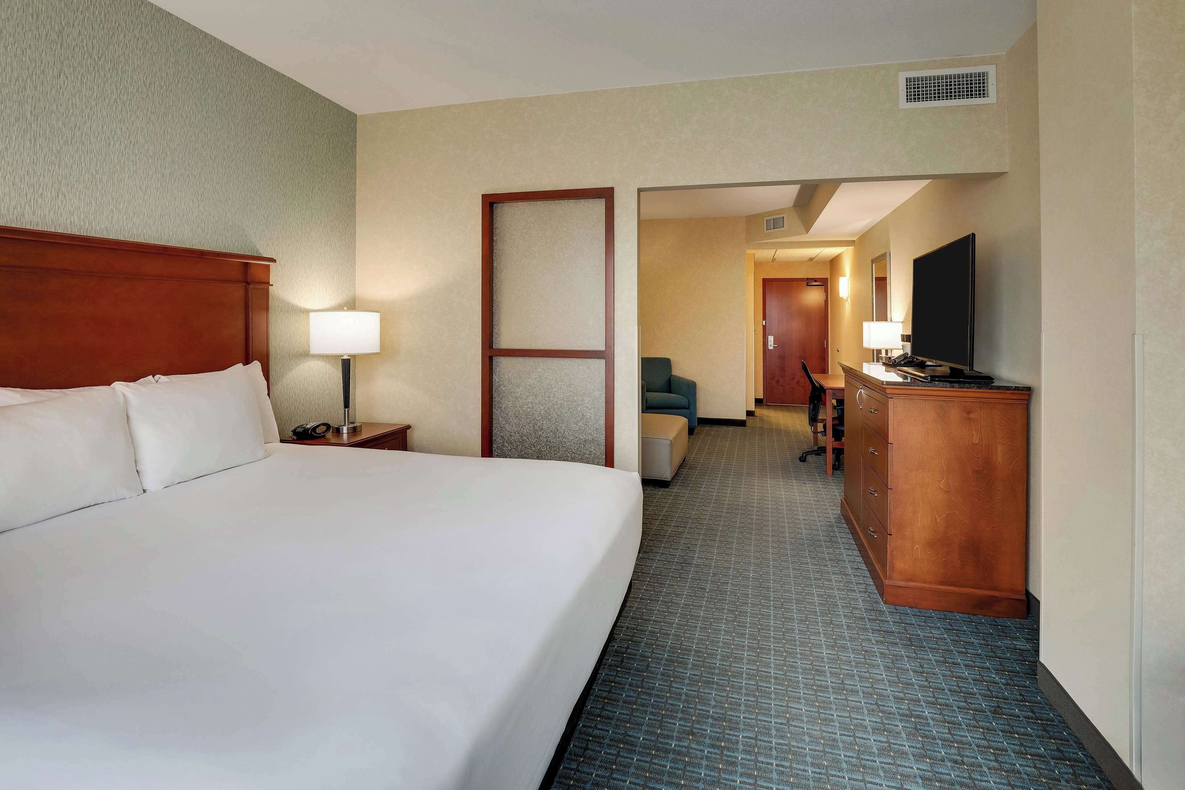 Una habitació d'hotel amb un llit gran, un escriptori amb televisió de pantalla plana, una cadira i un taulell.