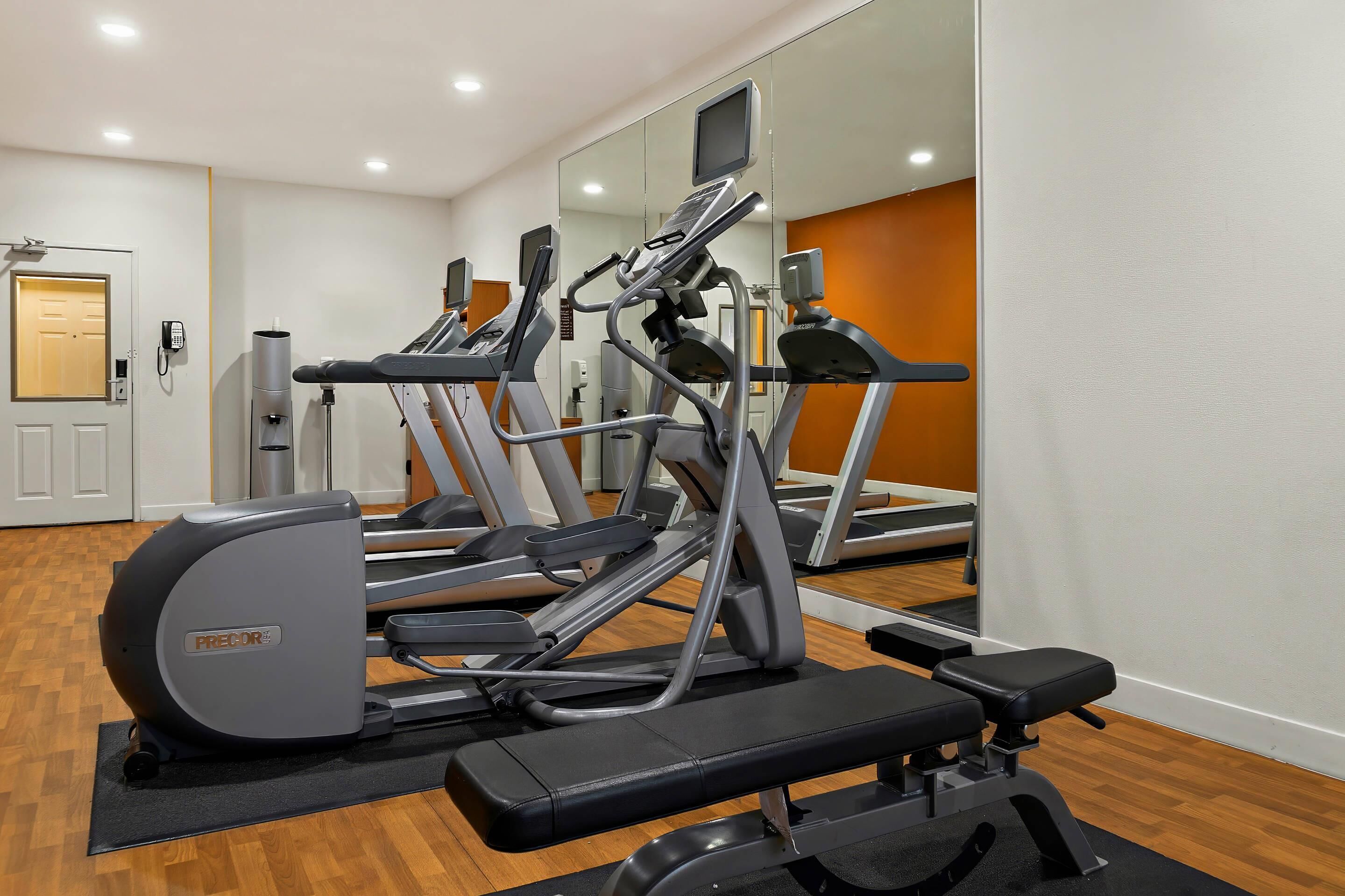 A gym with treadmills, a bench, and a water dispenser.