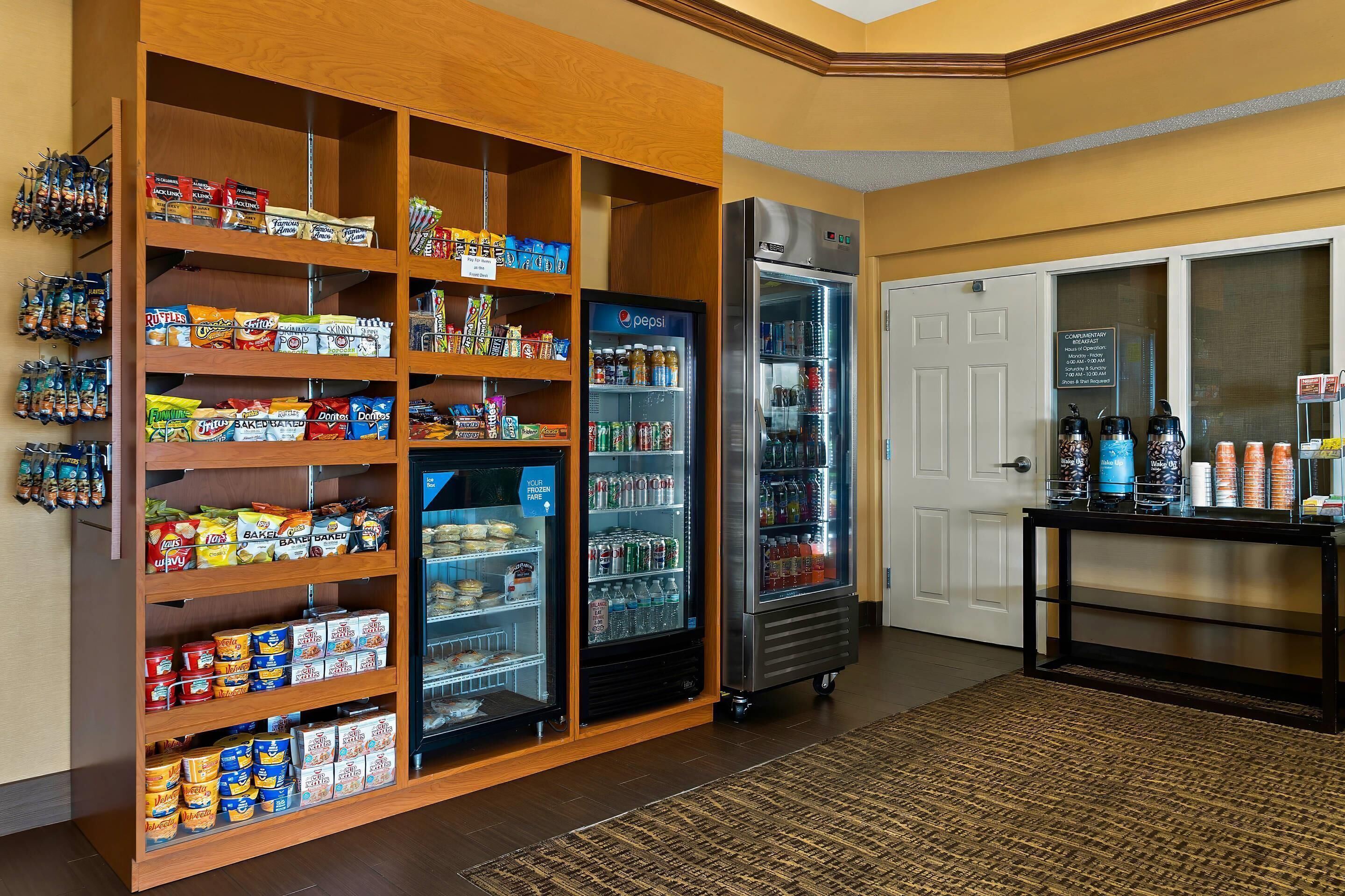 A snack and beverage area with shelves stocked with snacks and a refrigerator with beverages.