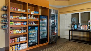 A snack and beverage area with shelves stocked with snacks and a refrigerator with beverages.