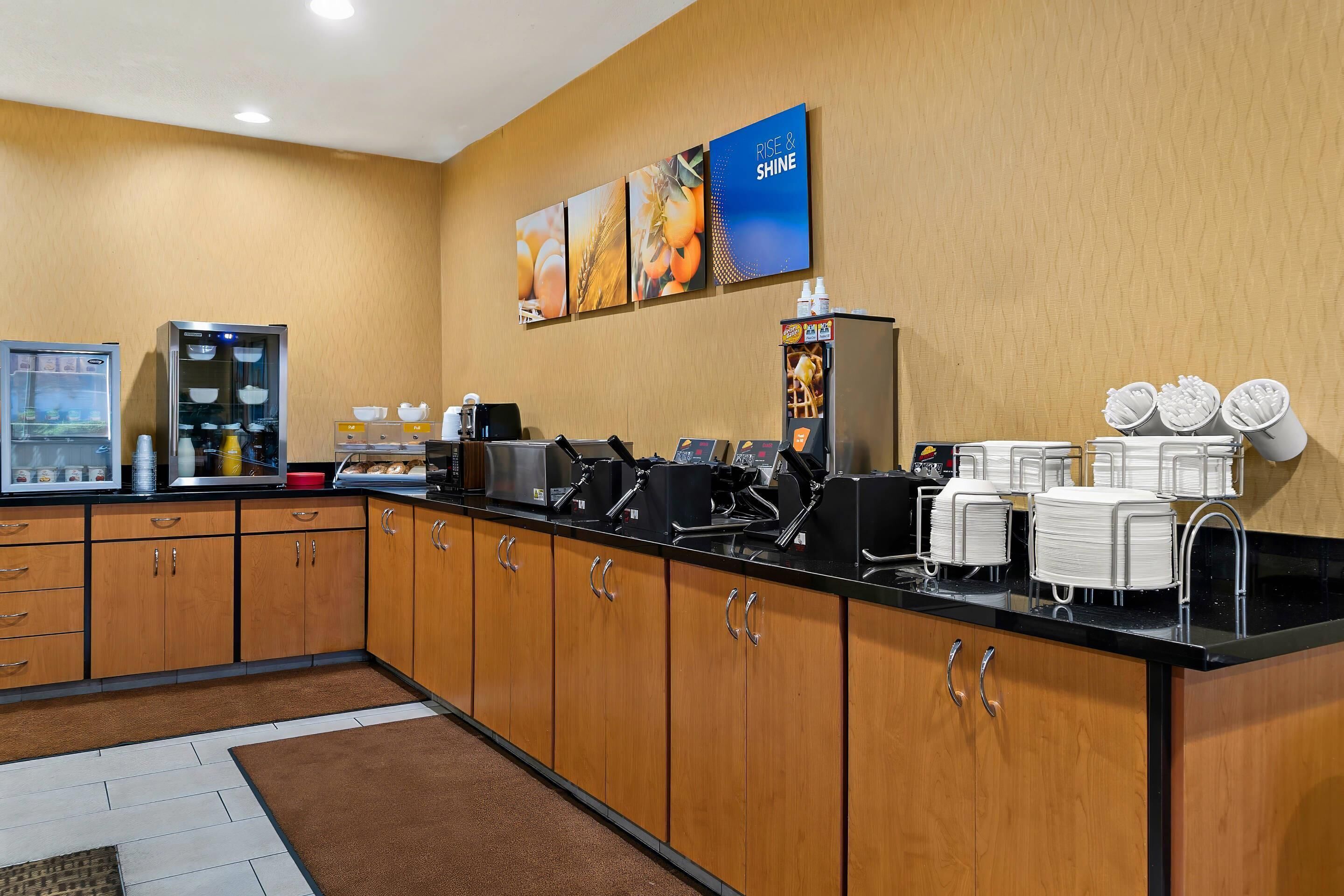 A hotel kitchen with a coffee station, a refrigerator, and a buffet area.