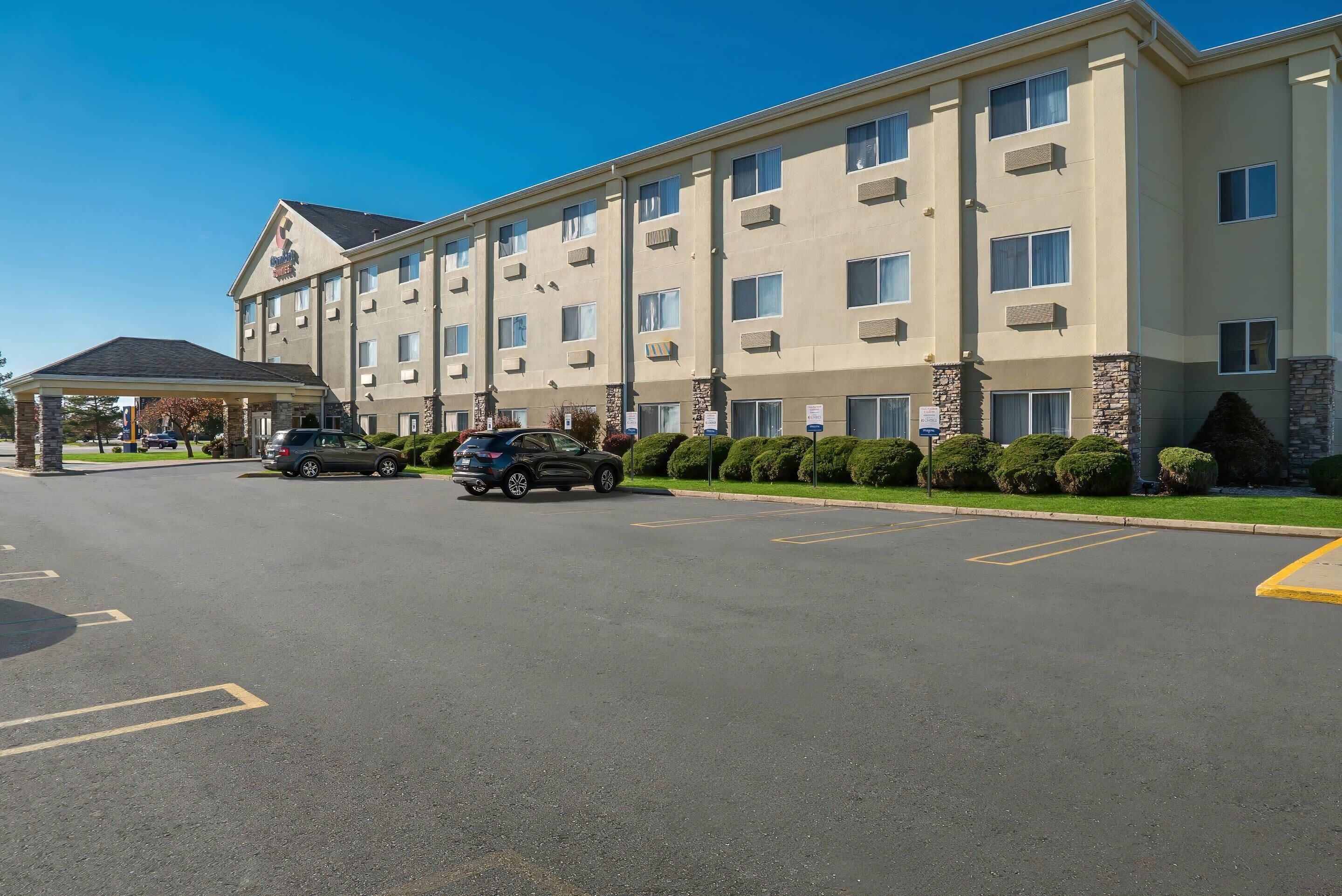 A multi-story hotel with a covered entrance and a parking lot.