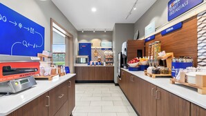 Een moderne ontbijtruimte met een flatscreen-tv, een koffiezetapparaat en verschillende ontbijtartikelen.