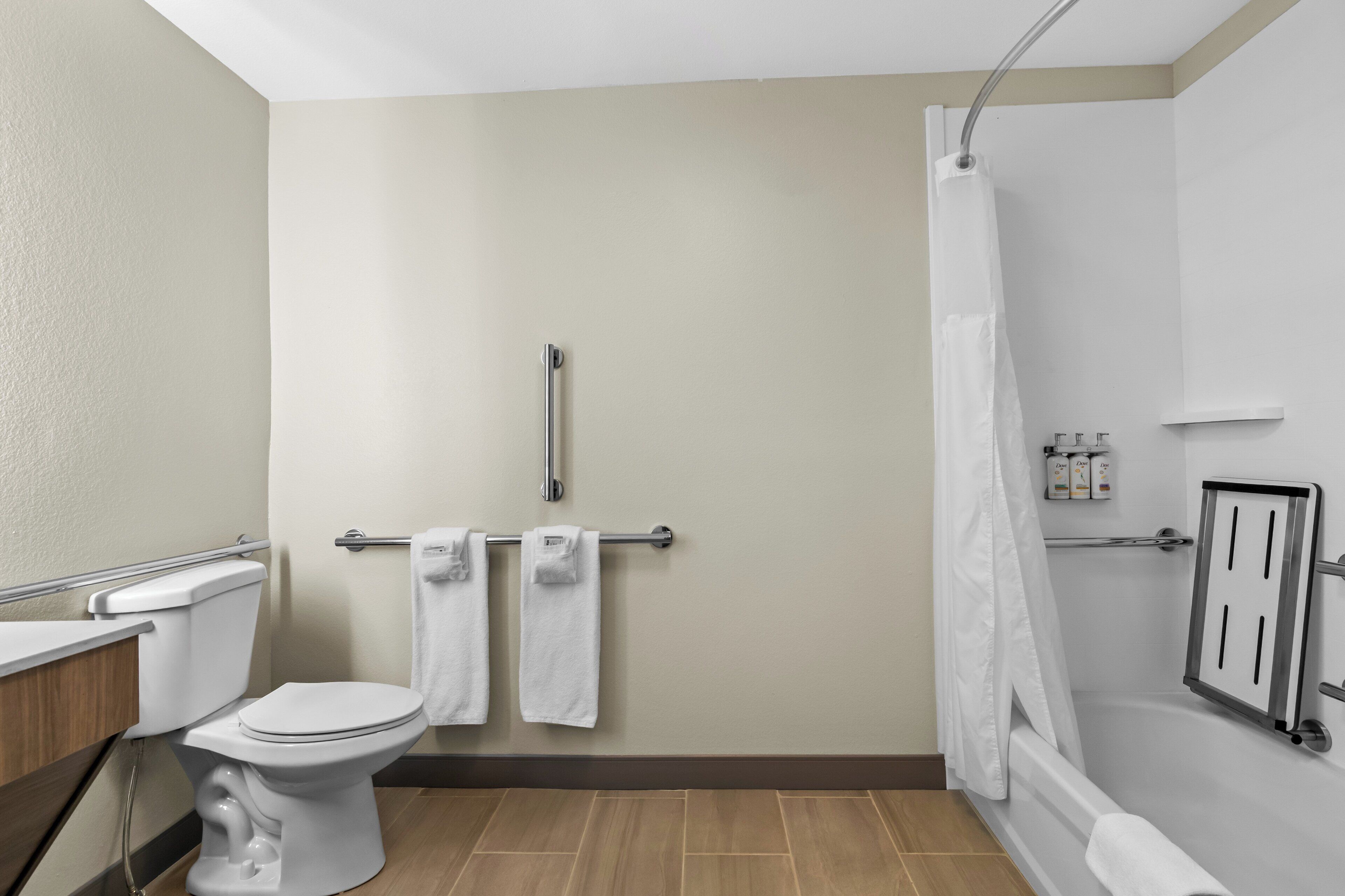 Un baño con inodoro, ducha con cortina y toallero con toallas.
