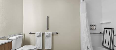 A bathroom with a toilet, a shower with a curtain, and a towel rack with towels.