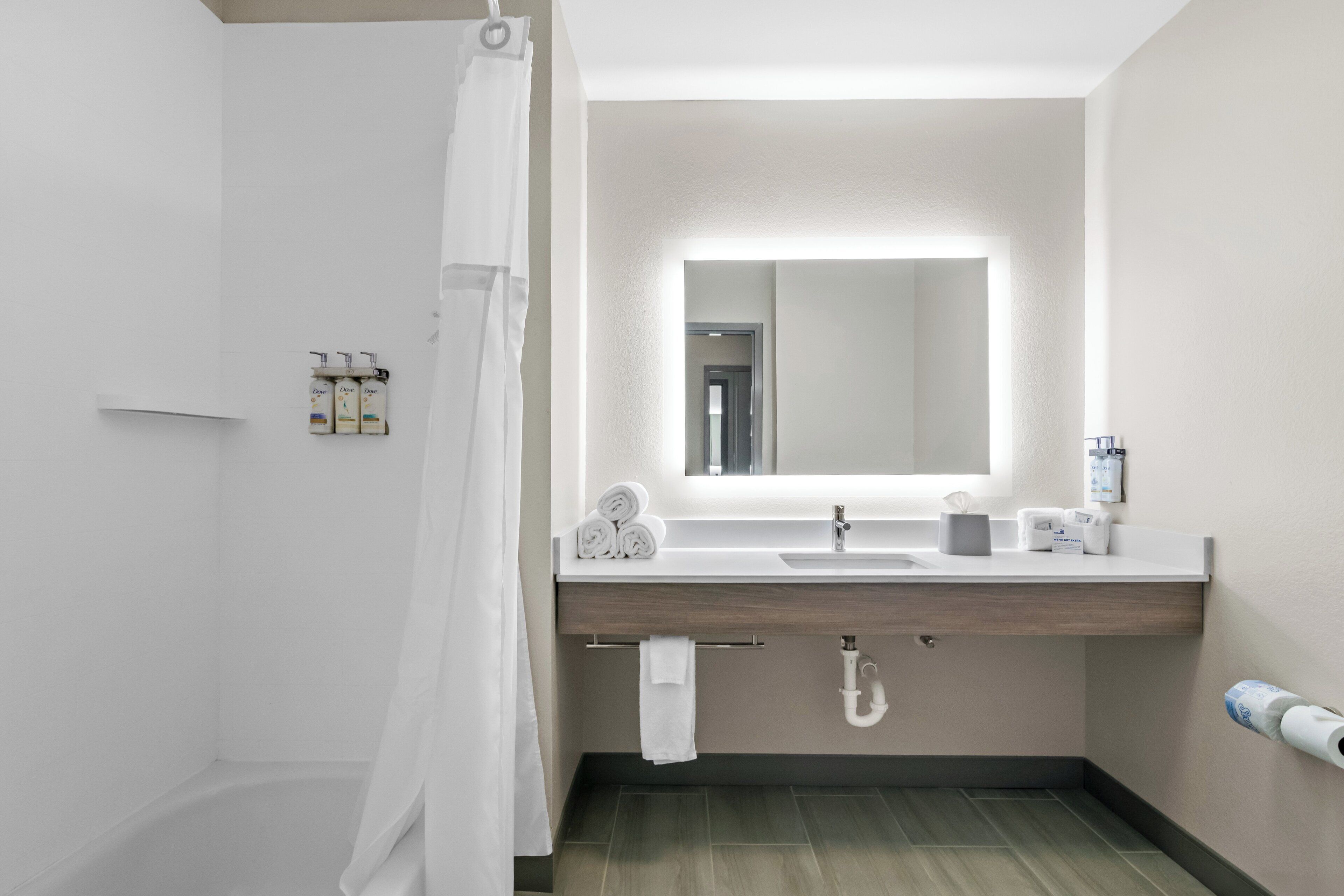A modern bathroom with a shower, a sink with a mirror, and toiletries on the wall.