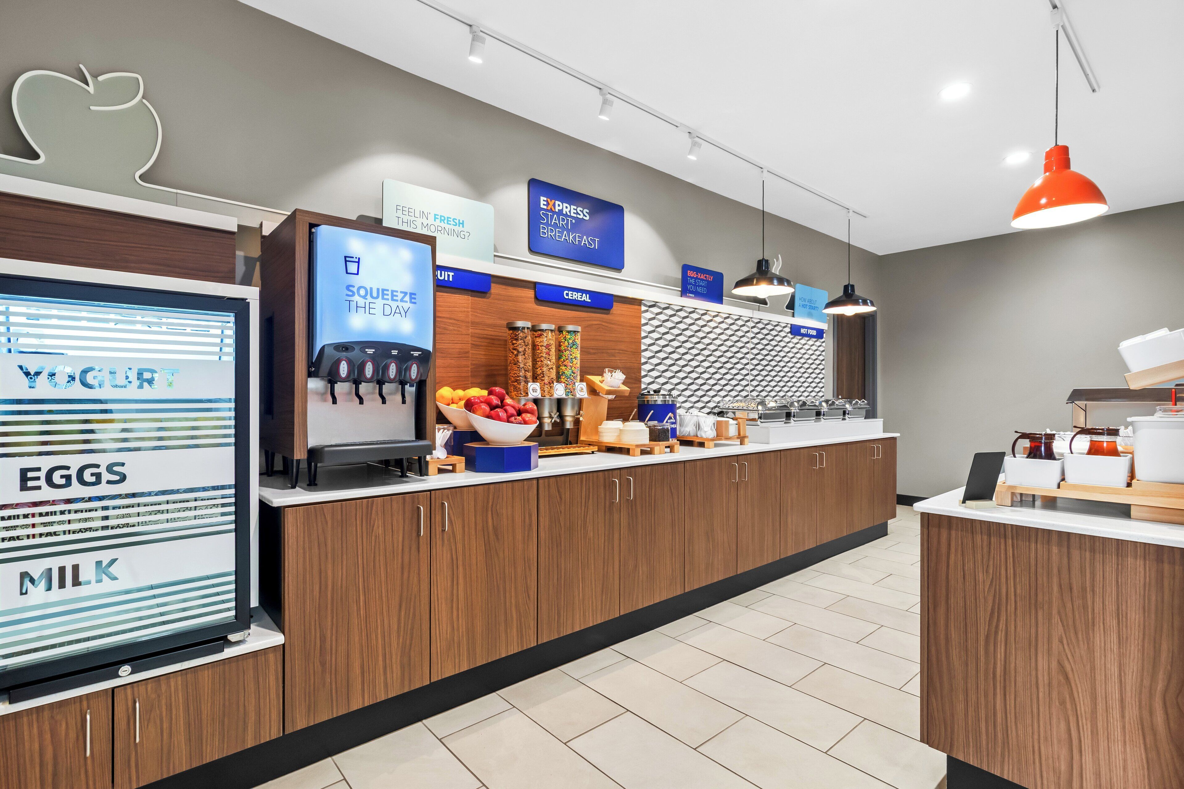 A modern breakfast area with a yogurt display, a fruit bowl, and a sign for express breakfast.