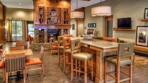 A spacious hotel lobby with a bar area, multiple seating options, and a fireplace.