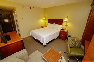 Una camera d'albergo con un letto, comodini, una scrivania, una sedia e una lampada.