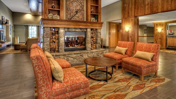 A spacious lobby with a stone fireplace, leather sofas, and a patterned rug.
