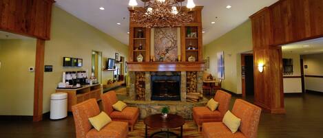 A spacious lobby with a fireplace, wooden paneling, and a chandelier.