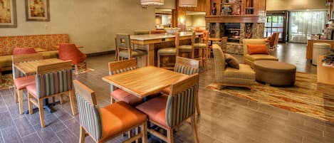 Un amplio vestíbulo de hotel con zona de comedor de madera, asientos cómodos y una chimenea.