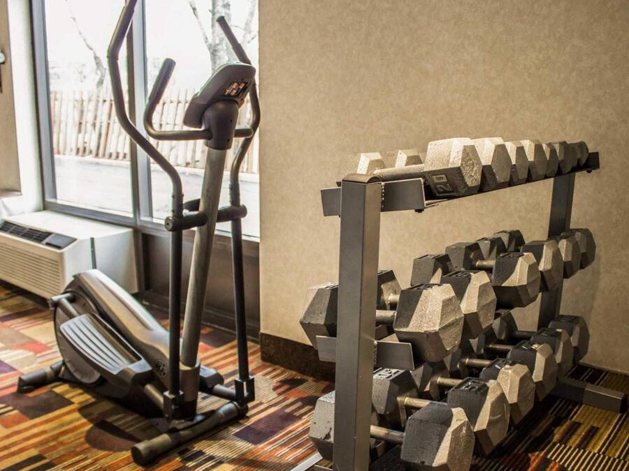 A gym with a stationary bike, elliptical, and a rack of dumbbells.