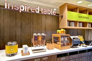A breakfast buffet area with a sign reading "inspired table," a coffee machine, and various food containers. - Home2 Suites by Hilton Bowling Green (Bowling Green)