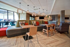 A modern lounge area with a sofa, chairs, a table, and pendant lighting. - Home2 Suites by Hilton Bowling Green (Bowling Green)