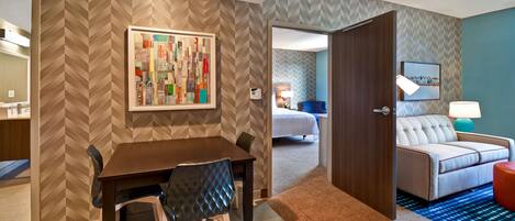 Une chambre d’hôtel comprenant un coin repas, un canapé, une lampe et un lit.