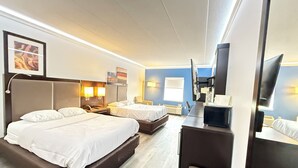 Een hotelkamer met twee bedden, een bureau, een flatscreen televisie en een grote spiegel.