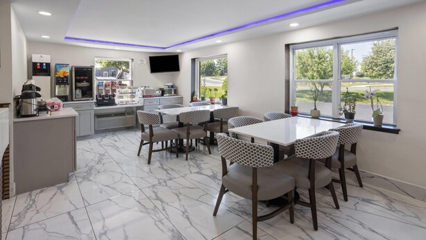 Een moderne keuken met een marmeren vloer, een centraal eiland en een zithoek met gestreepte stoelen en tafels.