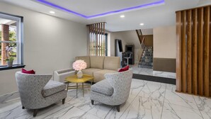 Een moderne woonkamer met een bank, twee fauteuils, een bijzettafeltje en een decoratieve vaas.