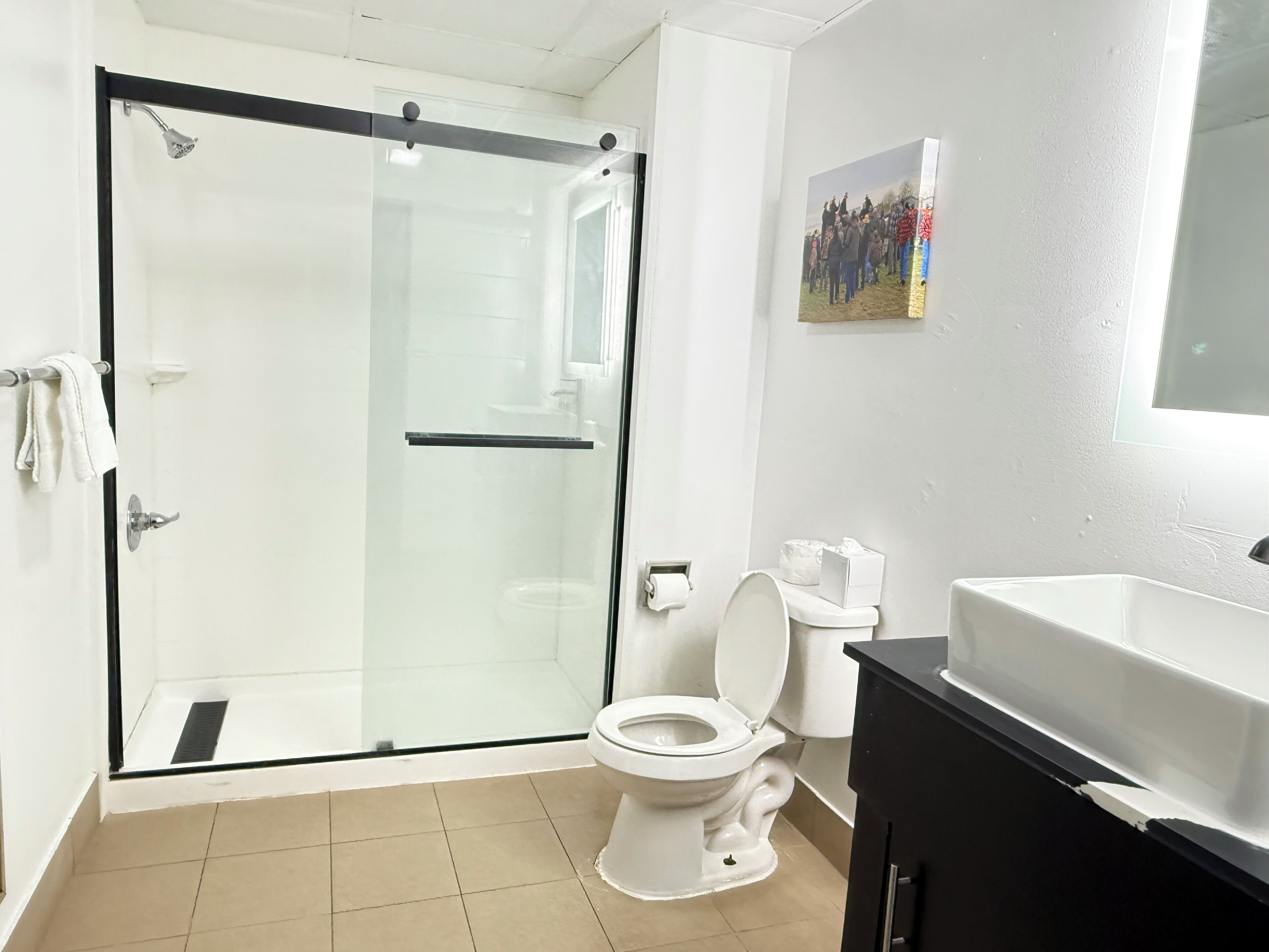 A bathroom with a glass shower enclosure, a toilet, and a sink.